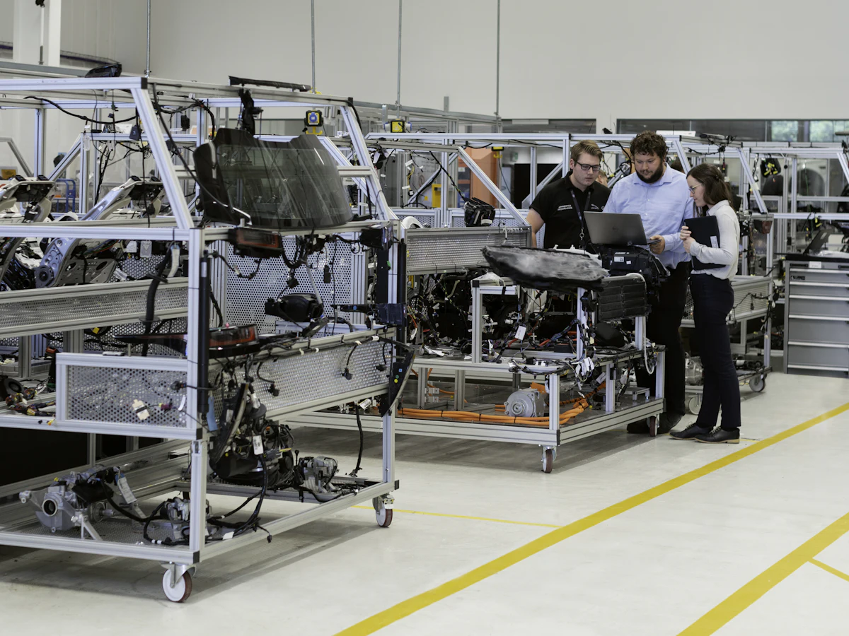 Three engineers reviewing a laptop together beside automotive testing equipment